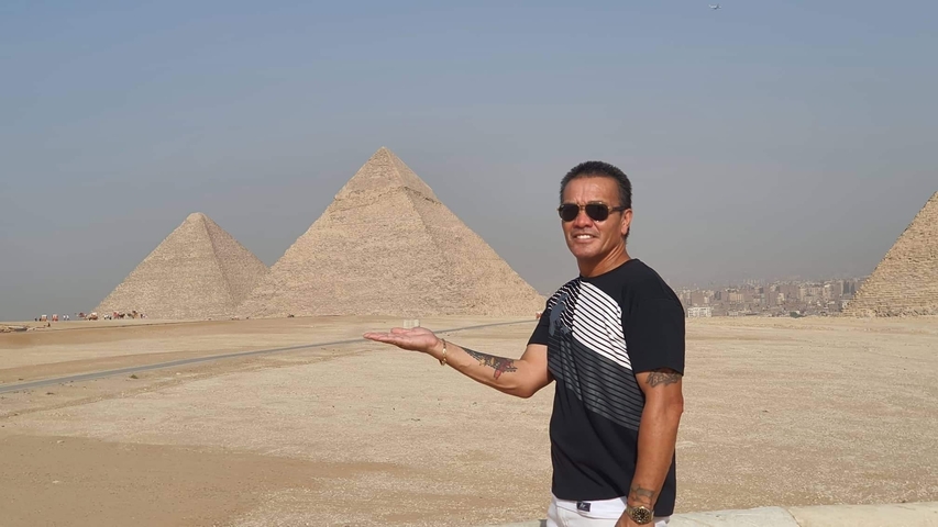       Man posing with Giza pyramids in the background.
  