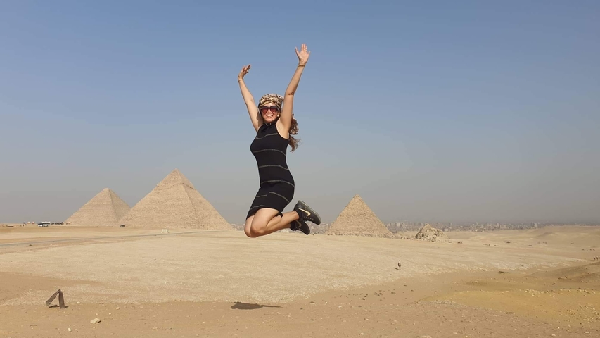 Woman jumping in front of Giza pyramids.