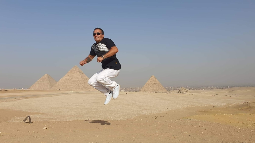 Man jumping in front of Giza pyramids.