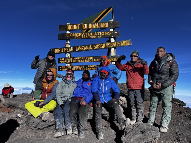 Group celebrating at the Uhuru Peak summit marker.