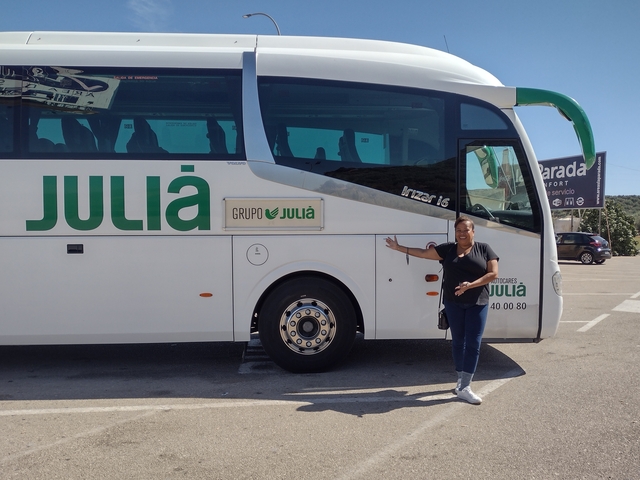 Woman posing next to a tour bus labeled 'Julia'.