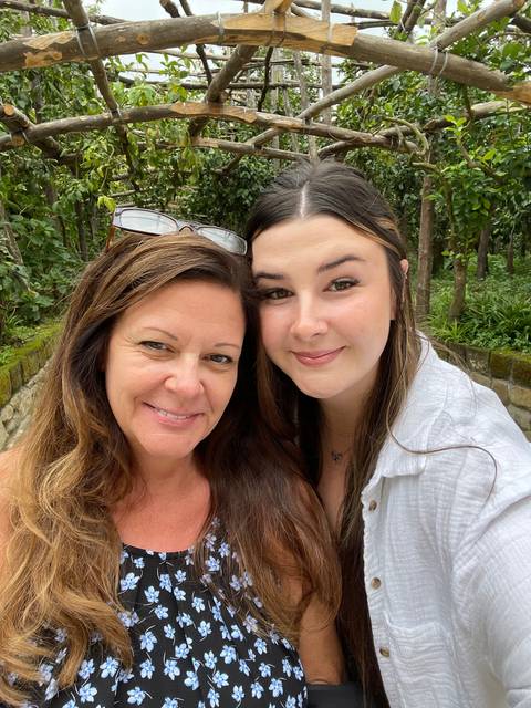 Selfie of two people outdoors with greenery behind