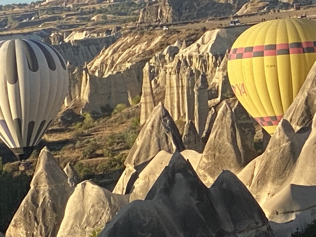 Hot air balloons floating over rock formations in Cappadocia.