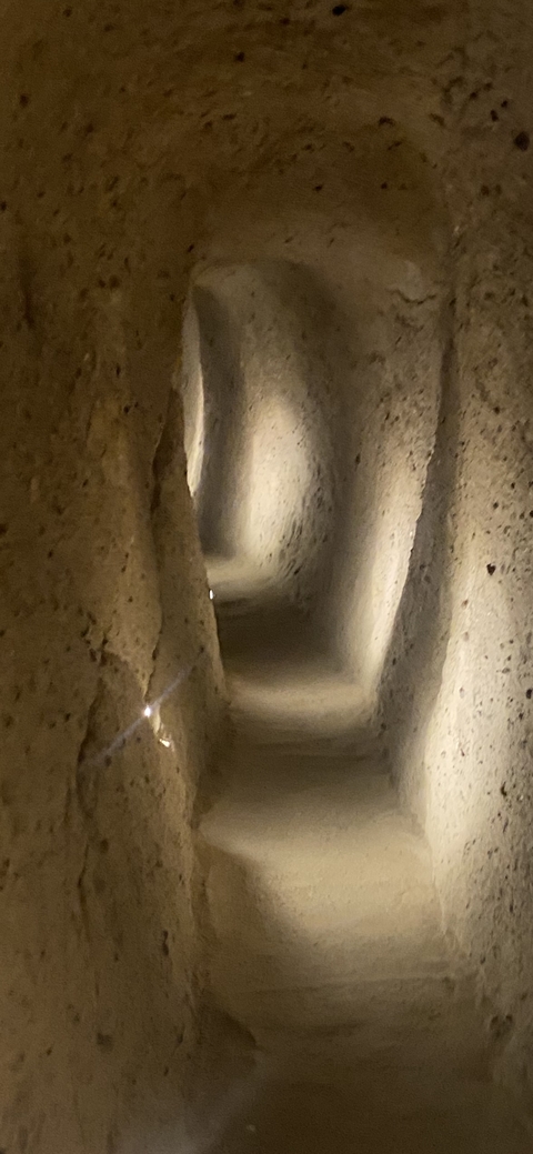 Inside a narrow cave tunnel with lights.