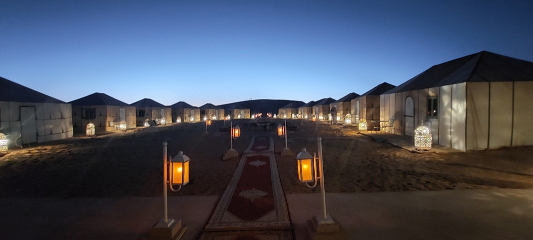       Desert camp with well-lit tents at night.
  