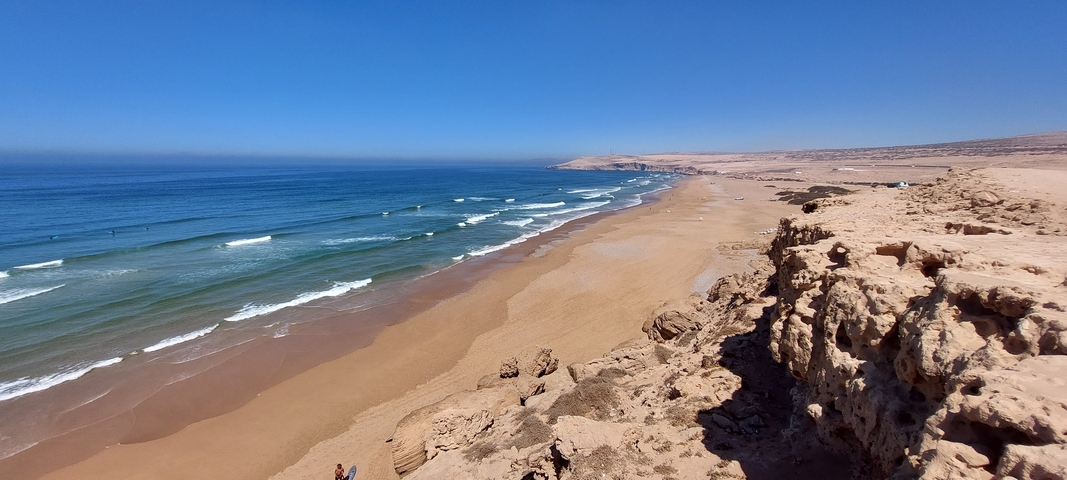 Seaside view with waves crashing onto a sandy beach.
