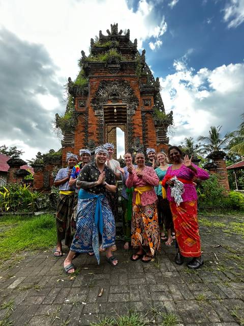 Group in traditional attire posing at a temple gate.