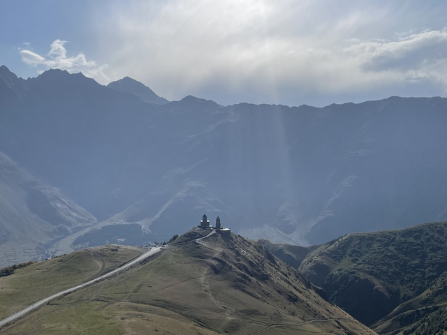       Silhouette of Gergeti Trinity Church with mountains in the background.
  
