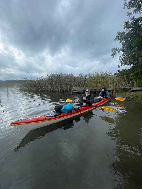 Two people in a kayak with paddles on a lake.