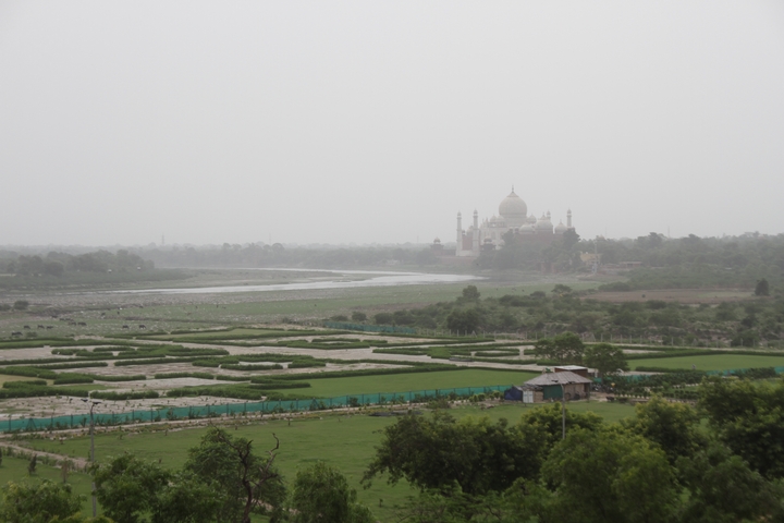 Distant view of the Taj Mahal across the river on a hazy day.