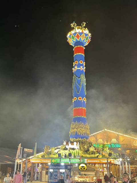 Colorful tall tower at night with festival lights.