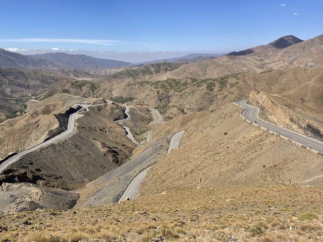       Winding mountain road amidst rocky terrain and vast landscapes.
  