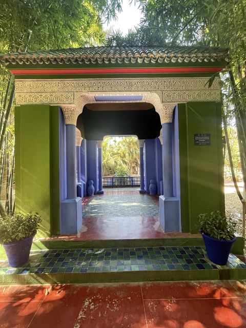       Lavish garden entrance with blue columns and lush greenery.
  