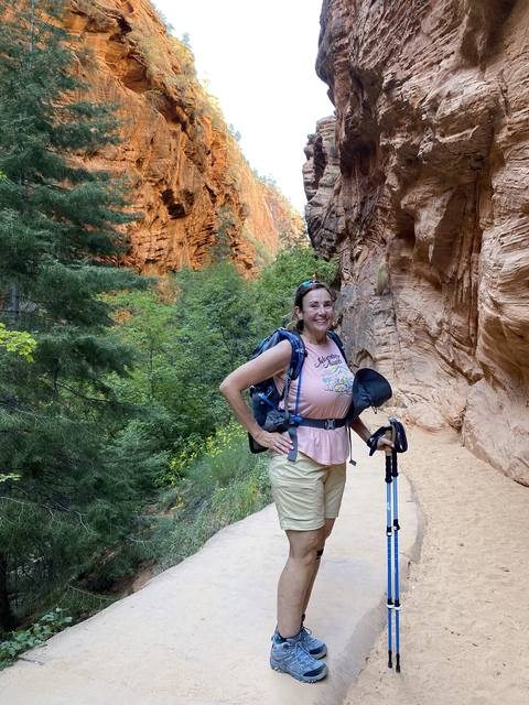       Woman hiking through green wilderness and orange canyon walls.
  