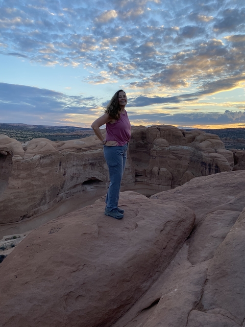       Woman posing on a rocky landscape with a colorful sunset.
  