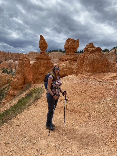       Woman trekking through orange hoodoos and rocky landscape.
  