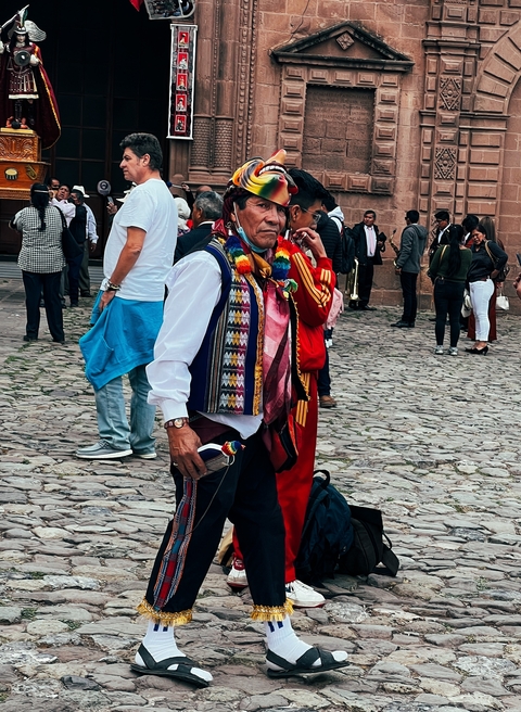 Man in traditional clothing in a busy street setting.