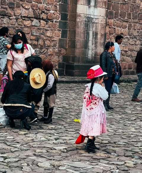 Children in traditional clothing standing in a cobblestone square.