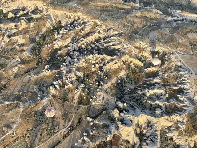 Aerial view of Cappadocia landscape with hot air balloons.