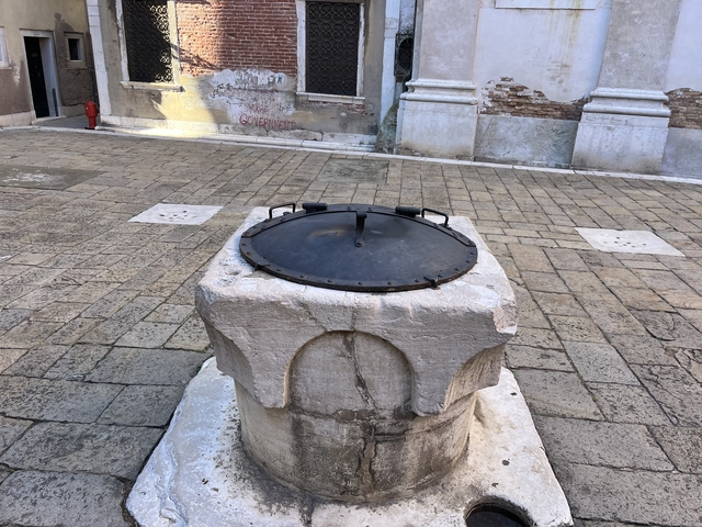 Stone structure with iron lid on a paved street.