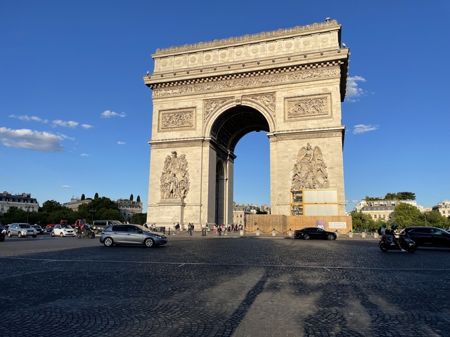 View of the Arc de Triomphe with traffic in the foreground.