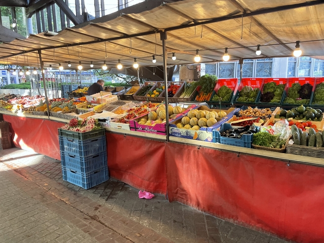 Outdoor market stall with various fruits and vegetables.