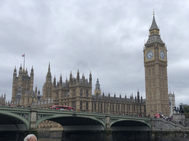       View of the Houses of Parliament and Big Ben with red bus crossing a bridge.
  