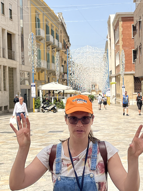 Person in sunglasses on a street with decorations.