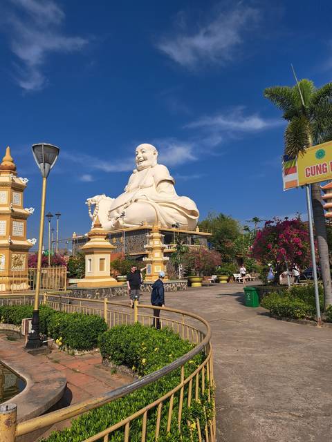       Large Buddha statue in a garden setting.
  