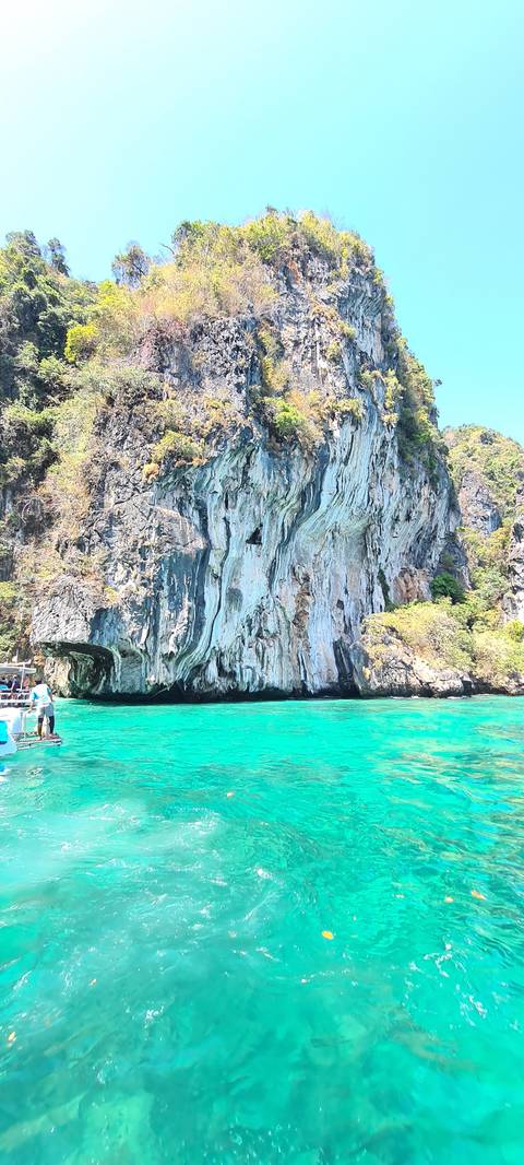       Emerald waters near towering limestone cliffs.
  