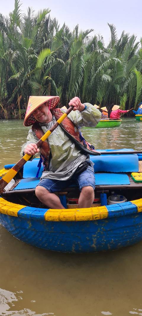       Person paddling in a traditional round bamboo boat.
  