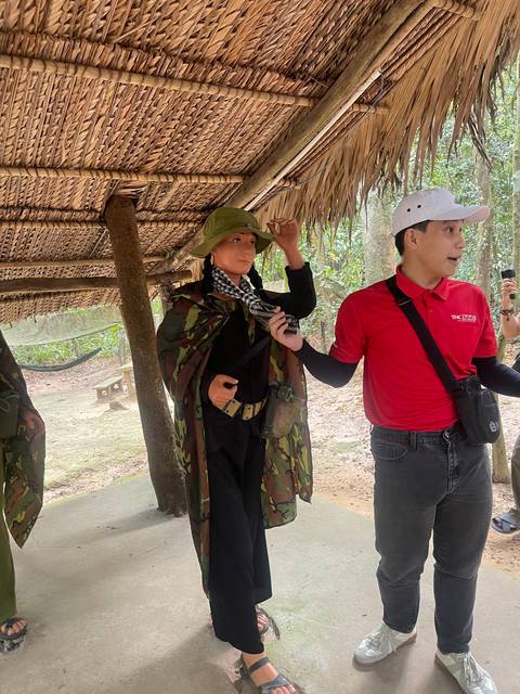       Tourists and a guide in a hut with thatched roof.
  