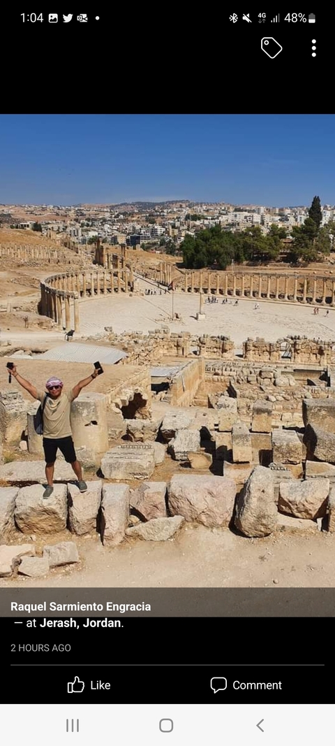 Man posing with arms raised in archaeological ruins
