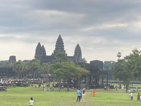      Angkor Wat temple with a reflection in the water, crowded with visitors.
  