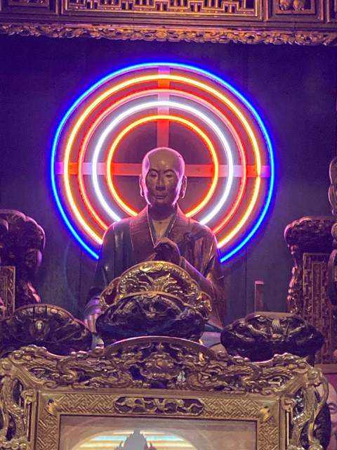 Statue with colorful neon lights in the background.