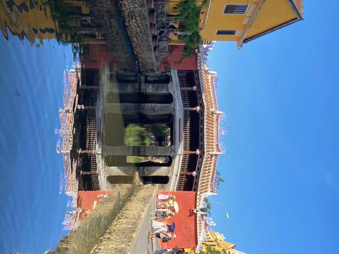       Decorative bridge over water with reflection, clear sky.
  