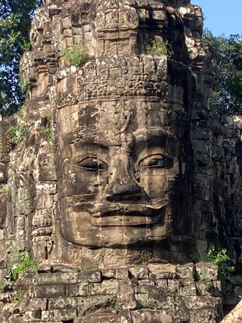       Large stone carving of a face on a temple wall.
  