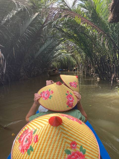 People paddling a boat through dense palm trees.