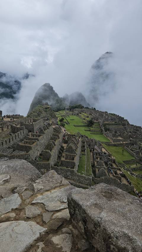       Panoramic view of Machu Picchu with clouds overhead.
  