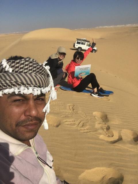 People sandboarding in the desert.