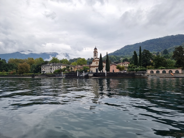 European lakeside village with a church, surrounded by mountains.