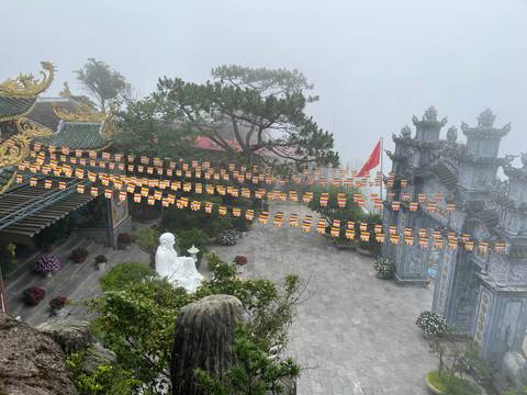 Detail of temple decorations with flags rising through fog.