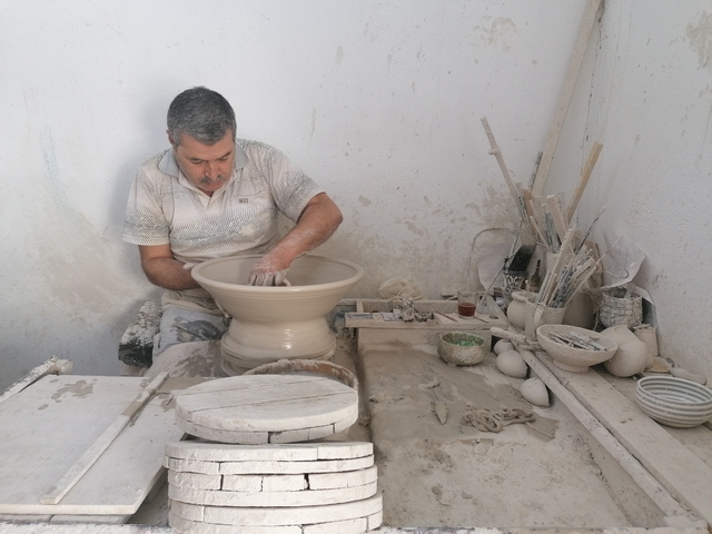       Man crafting pottery in a workshop.
  