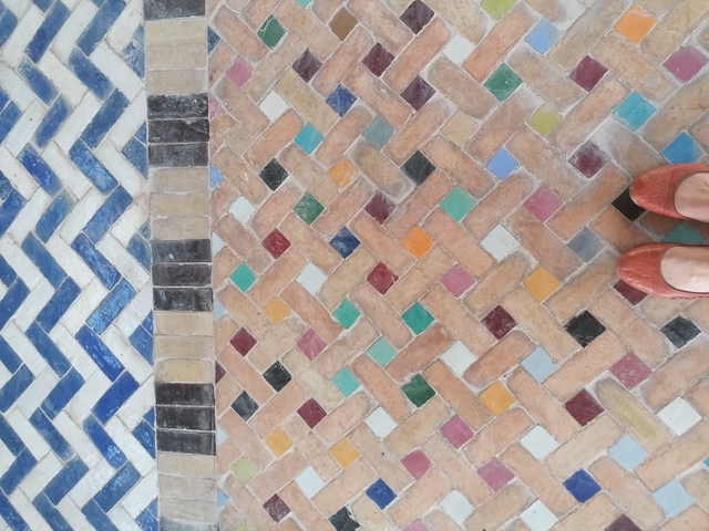       Colorful patterned tiles with a partial view of footwear.
  
