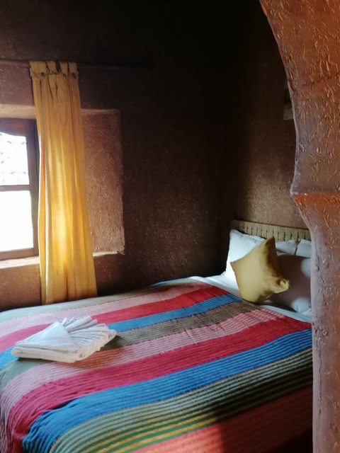       Interior of a bedroom with earthy textures and a single bed.
  