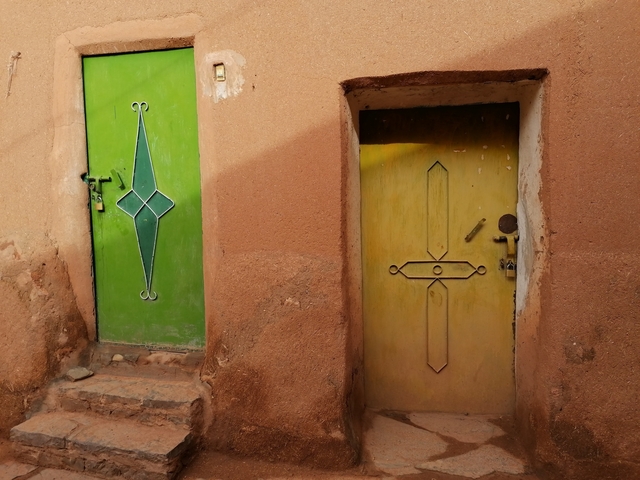       Two colorful doors in an adobe wall.
  