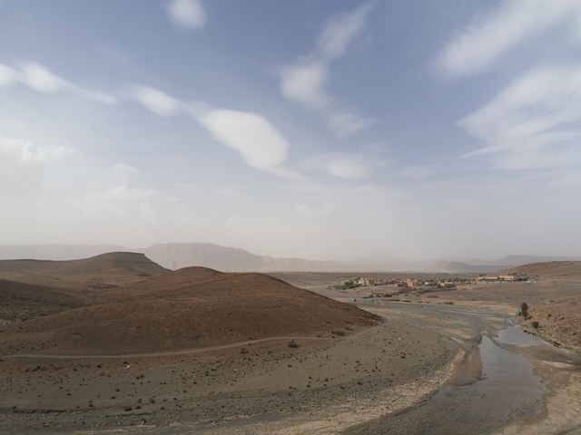       Arid desert landscape with a sparce town and hills.
  