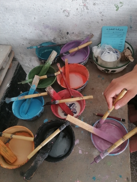       Hand painting with brushes and colorful paints.
  