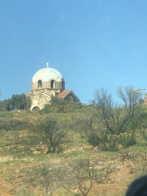 View of a hillside chapel with a dome and cross.