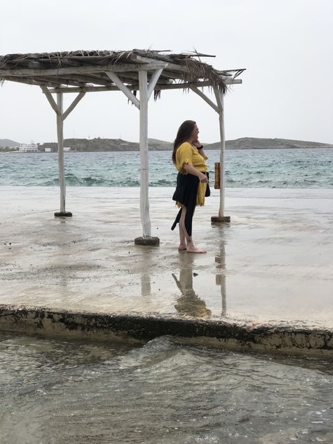 Person standing under a canopy by the sea.